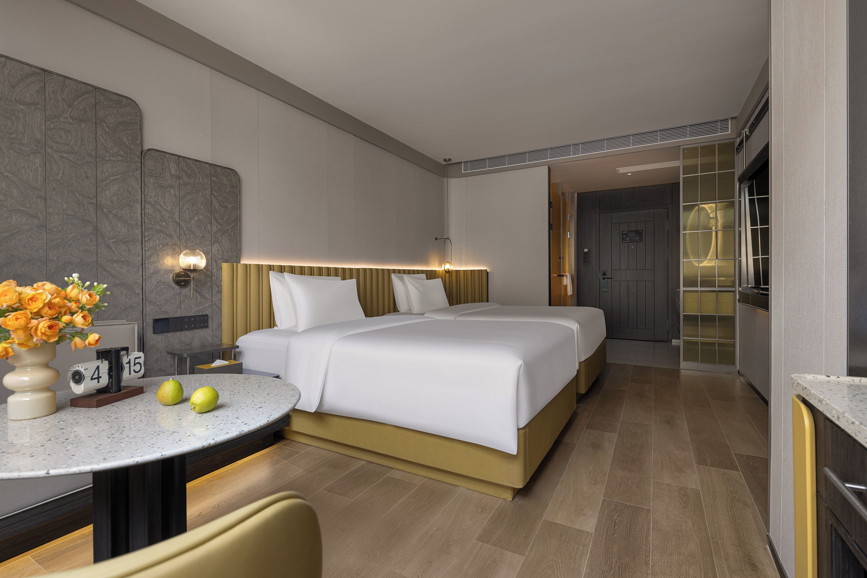Ein Hotelzimmer mit Bett, Nachttisch, Lampe, Blumen und einer Uhr.
