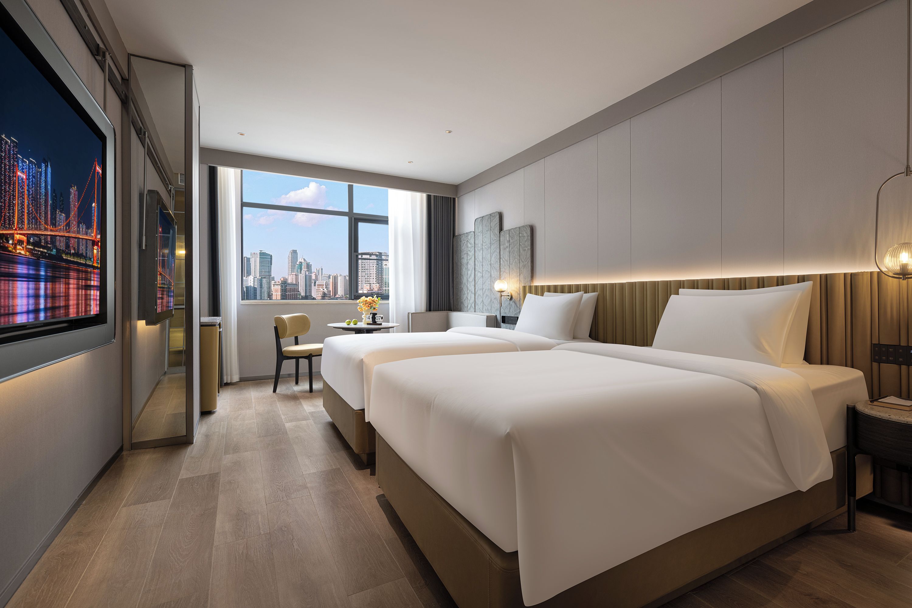 Une chambre d’hôtel avec deux lits, un bureau, une chaise, une télévision et une vue sur la ville.