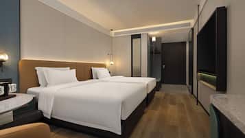 A hotel room with a double bed, a bedside table, a lamp, a mirror, and a TV mounted on the wall.