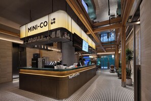A hotel lobby with a coffee station, reception desk, and a large window offering a view of the outdoors. - Feixiang Hotel Wuhan Jianghan Road Pedestrian Street (wuhan)