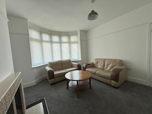 A living room with two beige sofas, a round coffee table, and a fireplace. - Central Peterborough Home, Garden, Parking, 2 Bed (Peterborough)