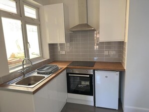 A compact kitchen with a sink, stove, oven, and a small refrigerator. - Central Peterborough Home, Garden, Parking, 2 Bed (Peterborough)