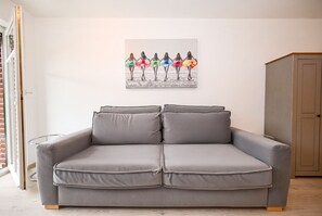 A grey sofa with two cushions in a room with a white wall. - Nordlicht Vacation Rental in Büsum: Your Fabulous Vacation by the Sea (Büsum)
