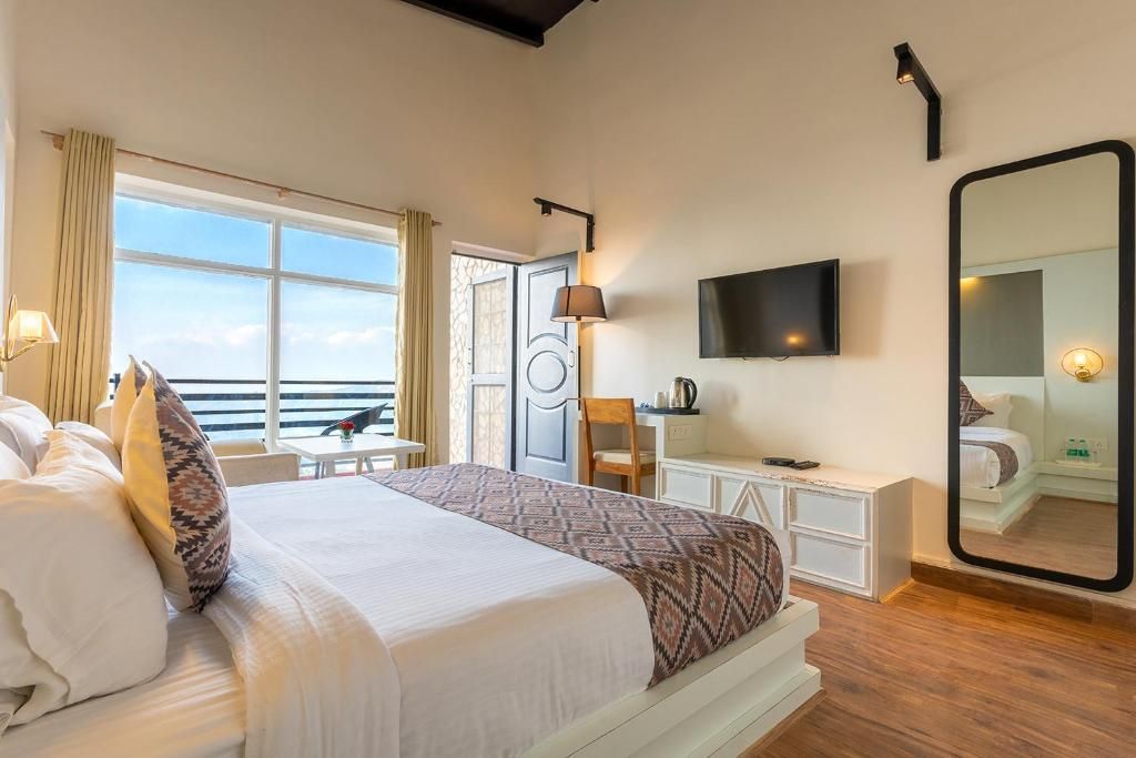 Una habitación de hotel con una cama, un escritorio, una silla, un televisor y un espejo grande.