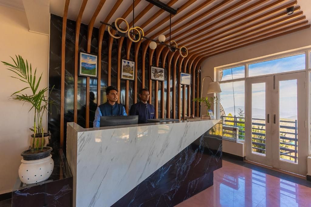 Zona de recepción con mostrador de mármol, listones de madera y cuadros en la pared.