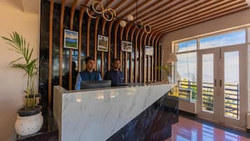 Zona de recepción con mostrador de mármol, listones de madera y cuadros en la pared.