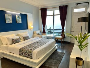 A hotel room with a bed, a desk, a chair, a plant, and a view of the outdoors. - Himalayas Resort by The Lake Hill (Nainital)