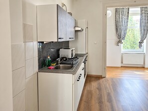 A kitchen with white cabinets, a microwave, a stove, and a sink. - Vienna City Break 2BR near Stadthalle (Wien)