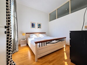 A bedroom with a wooden bed, a nightstand, a lamp, and a black wardrobe. - Vienna City Break 2BR near Stadthalle (Wien)