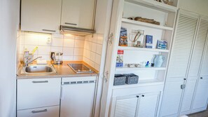 A compact kitchen with a sink, stove, and storage cabinets. - Deichnest Vollerwiek Apartment: A Relaxing Getaway by the Sea (Vollerwiek)