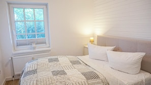 A bedroom with a bed, a window, a radiator, and a bedside lamp. - Deichnest Vollerwiek Apartment: A Relaxing Getaway by the Sea (Vollerwiek)