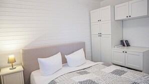 Een slaapkamer met een bed, nachtkastje en een witte kledingkast.