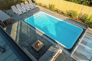 Una piscina sul tetto con lettini, un braciere e un tavolo.