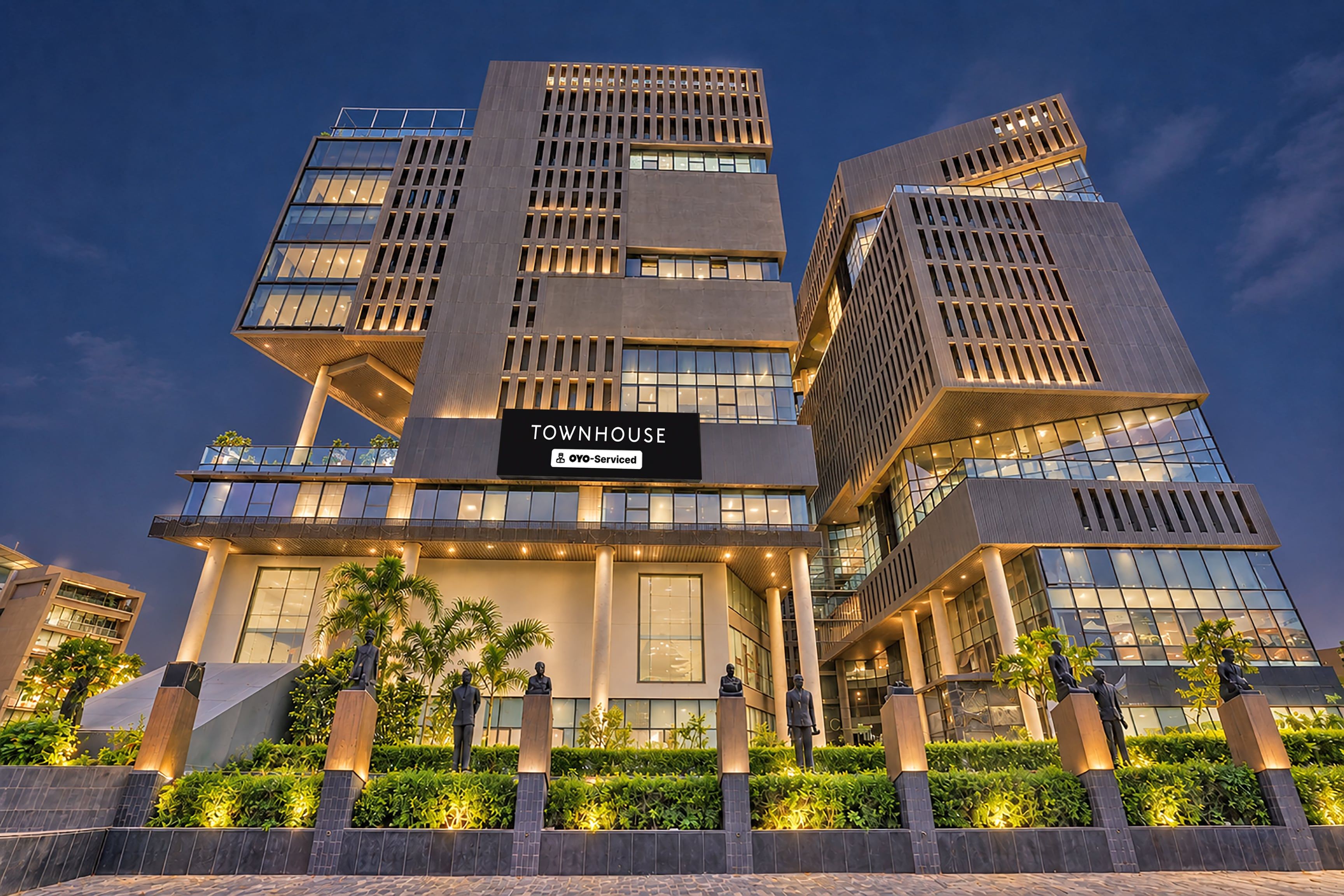 A modern building with multiple floors, a prominent sign reading 'TOWNHOUSE,' and a well-lit entrance.