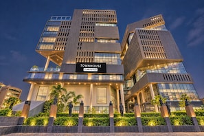 Un edificio moderno con varios pisos, un letrero destacado que dice 'TOWNHOUSE' y una entrada bien iluminada.