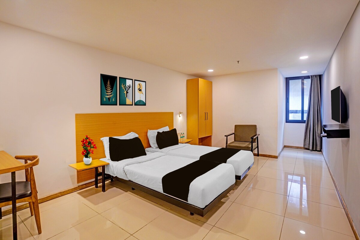A hotel room with a bed, a desk, a chair, a television, and artwork on the wall.