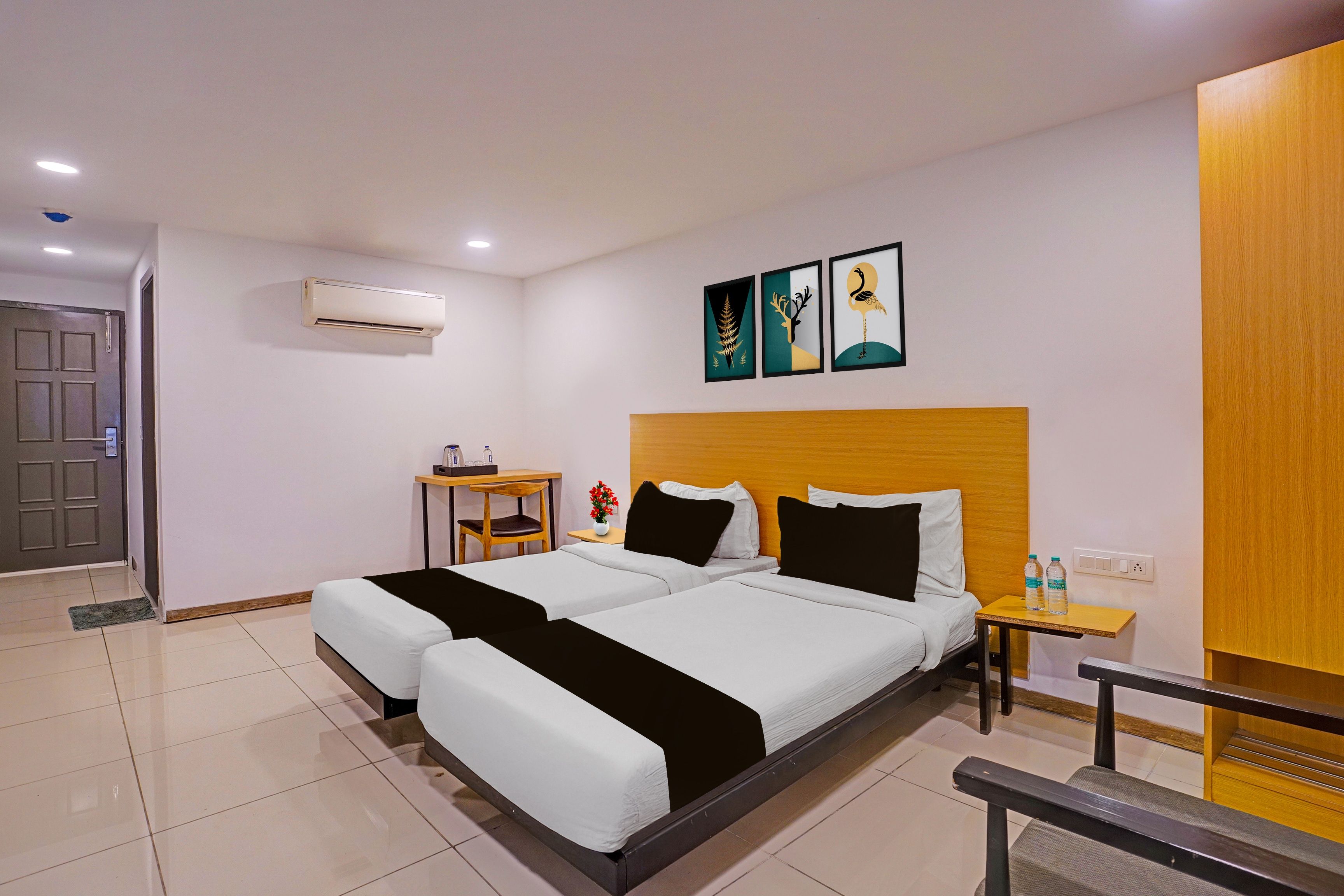 Habitación de hotel con cama doble, escritorio, silla, equipo de aire acondicionado y una obra de arte en la pared.