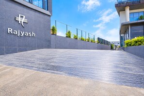 A modern building entrance with a sign reading 'Rajyash' and a paved pathway leading to the entrance. - Townhouse APMC Metro Station  (Ahmedabad)