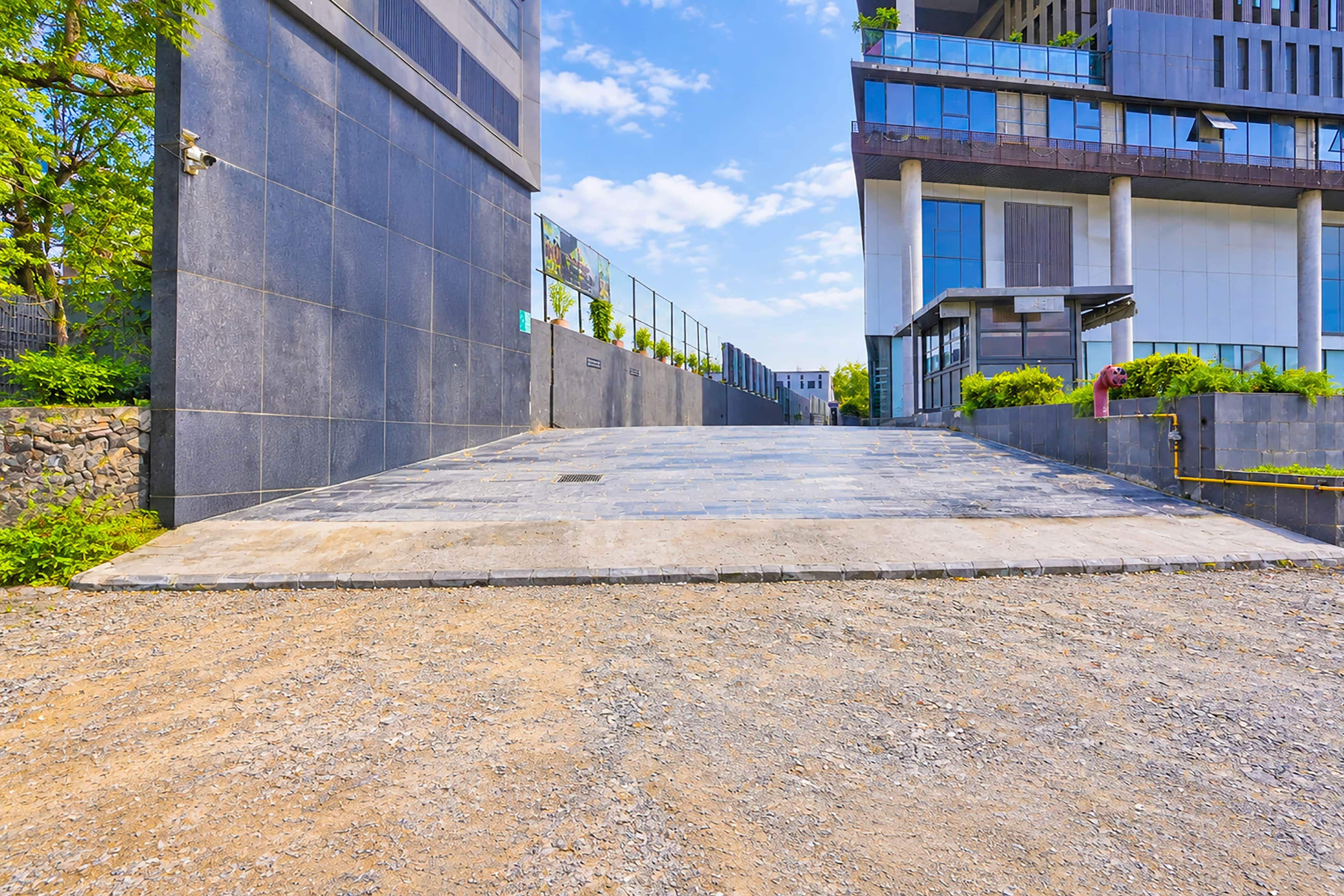 Un camino pavimentado que conduce a un edificio moderno con techo plano y ventanas amplias.