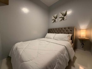 A bedroom with a single bed, a nightstand with a lamp, and two wall-mounted artworks. - Cozy condo unit at the heart of Metro Manila, Near Mall of Asia and Airports (Pasay City)