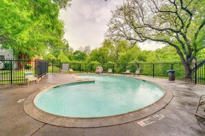 Ein runder Pool mit umgebendem Zaun, Liegestühlen und Bäumen im Hintergrund.
