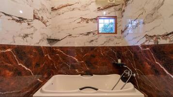 A bathroom with a marble wall and a bathtub.