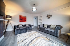 Ein modernes Wohnzimmer mit zwei Sofas, einer Stehlampe und einem großen abstrakten Gemälde.
