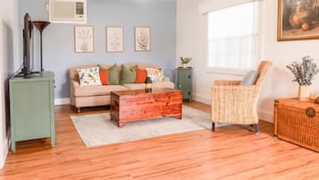 A living room with a sofa, a wooden coffee table, a wicker chair, and a small cabinet.