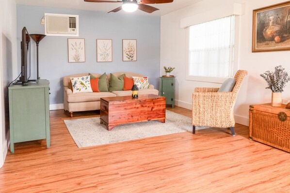 A living room with a sofa, a wooden coffee table, a wicker chair, and a small cabinet. - defaultName (Land O` Lakes)