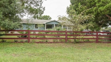 A house with a fenced yard, surrounded by trees and vegetation.