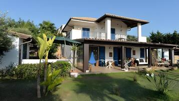 Een huis met twee verdiepingen, een balkon, een overdekt terras en een verzorgde tuin.