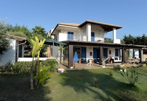 Een huis met twee verdiepingen, een balkon, een overdekt terras en een verzorgde tuin.
