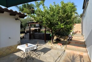 A patio with a table and chairs, a pergola, and a tree. - Holiday home 'Sunset House' with pool, outdoor kitchen and Wi-Fi (Agrigento)