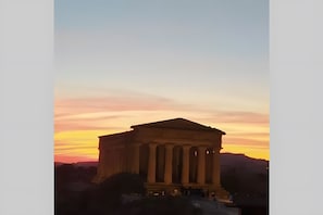 Een klassiek gebouw met kolommen, waarschijnlijk een historisch monument, voor een zonsondergang.