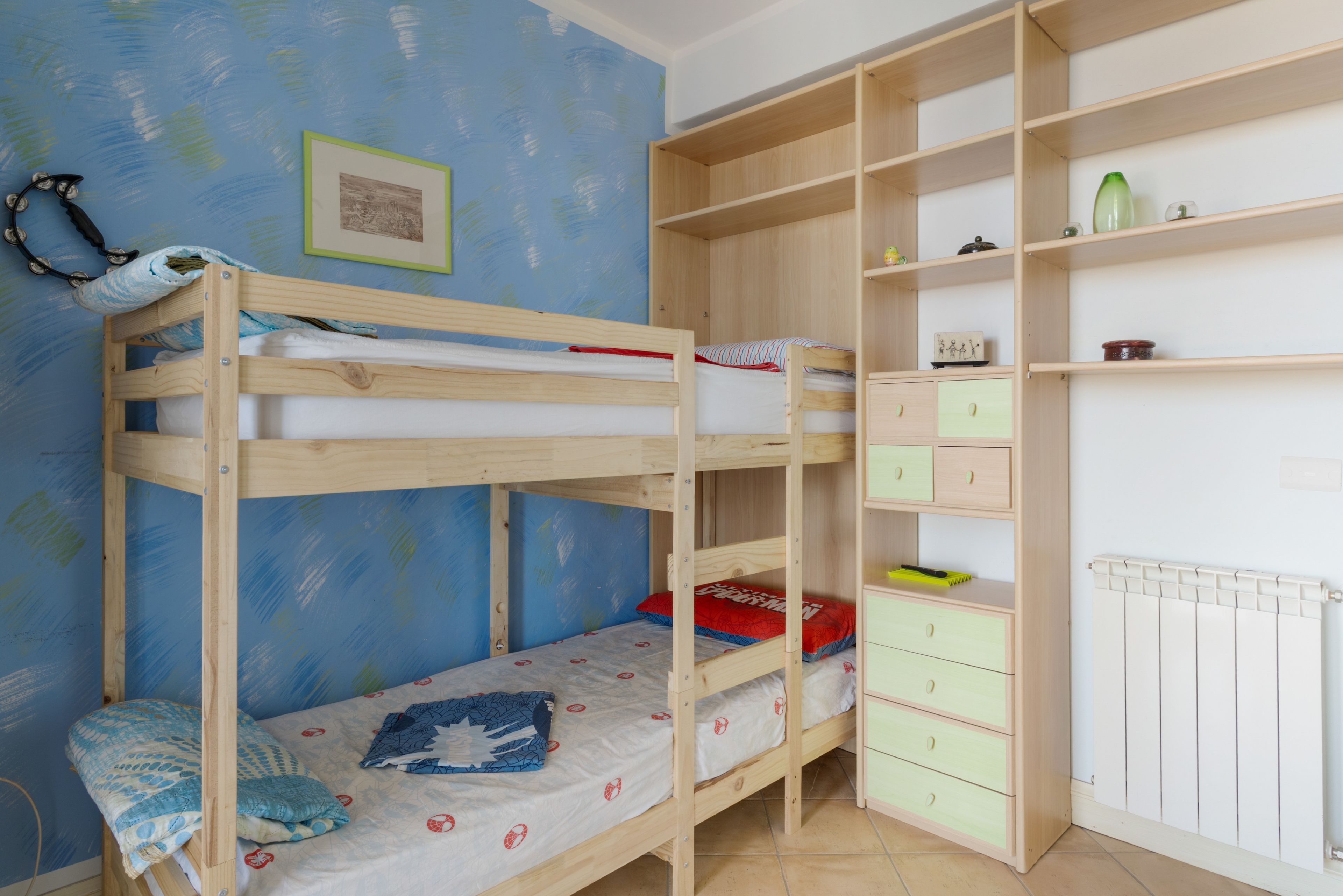 A bunk bed with a lower bunk, a small desk with drawers, and a radiator.