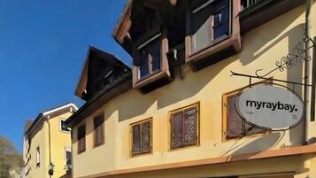 Un edificio con un cartello che riporta 'myraybay'. Presenta diverse finestre con persiane, un'antenna parabolica e un'insegna decorativa in metallo.