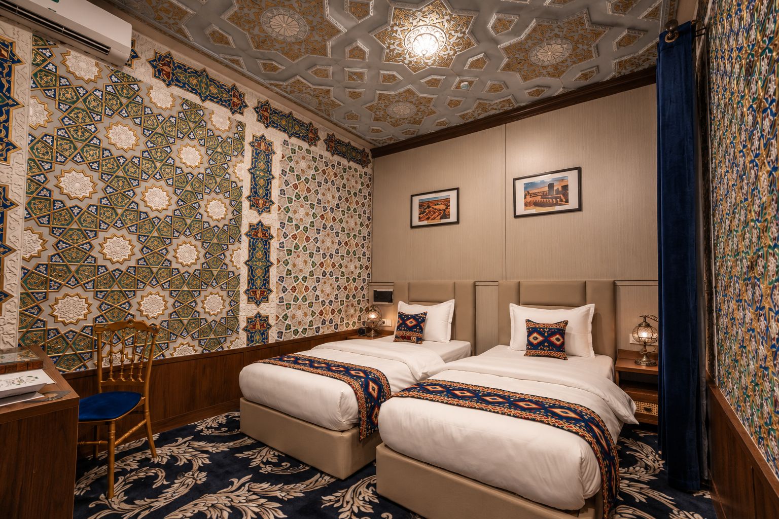 Habitación de hotel con dos camas, un escritorio, una silla y un papel tapiz estampado.