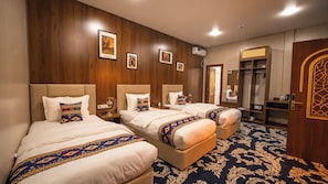 A hotel room with three beds, a wardrobe, a mirror, and a patterned carpet. - Old Bazaar Boutique Hotel (Buxoro)