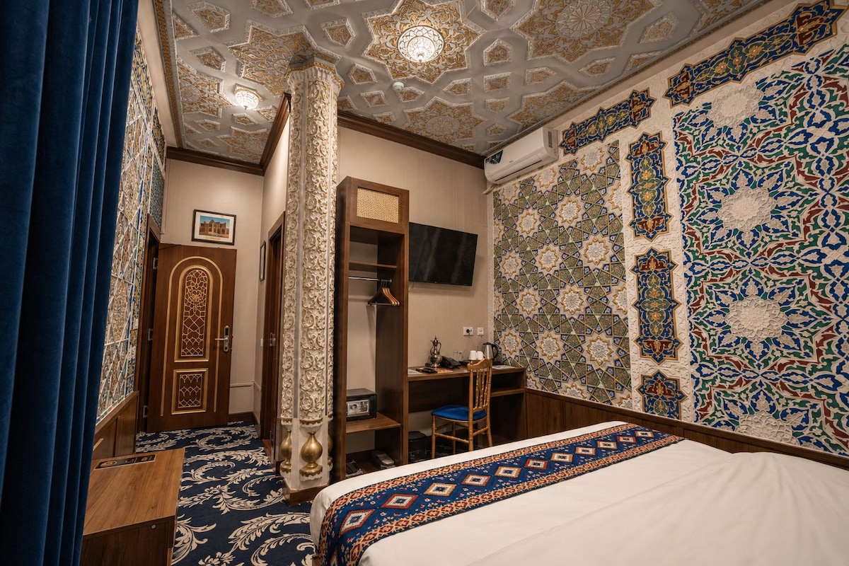 Una habitación de hotel con una cama grande, un armario, un escritorio y una televisión.