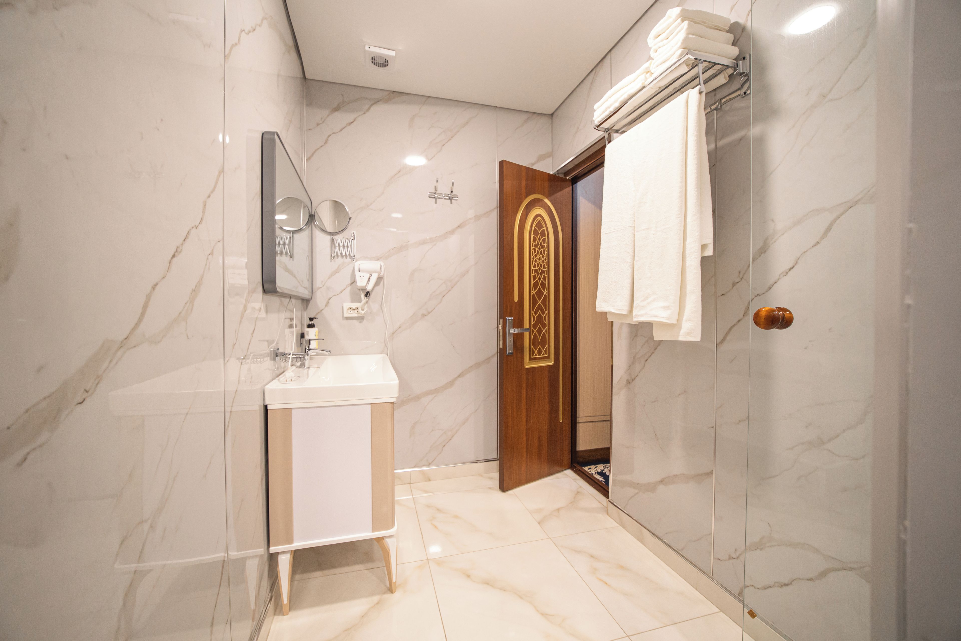A modern bathroom with a marble floor, a sink, a mirror, and a towel rack.