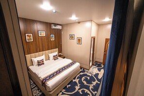 Una habitación de hotel con una cama, una mesita de noche, un espejo y cuadros en la pared.