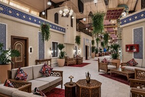 Un hall amplio con decoración tradicional, disposición de asientos y plantas colgantes.