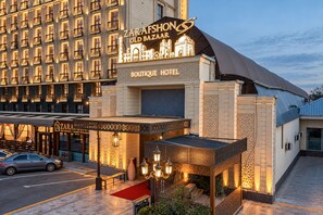 Un hotel con un cartel llamativo que indica 'ZARAFSHON OLD BAZAAR' y 'BOUTIQUE HOTEL', mostrando también un restaurante de fusión.