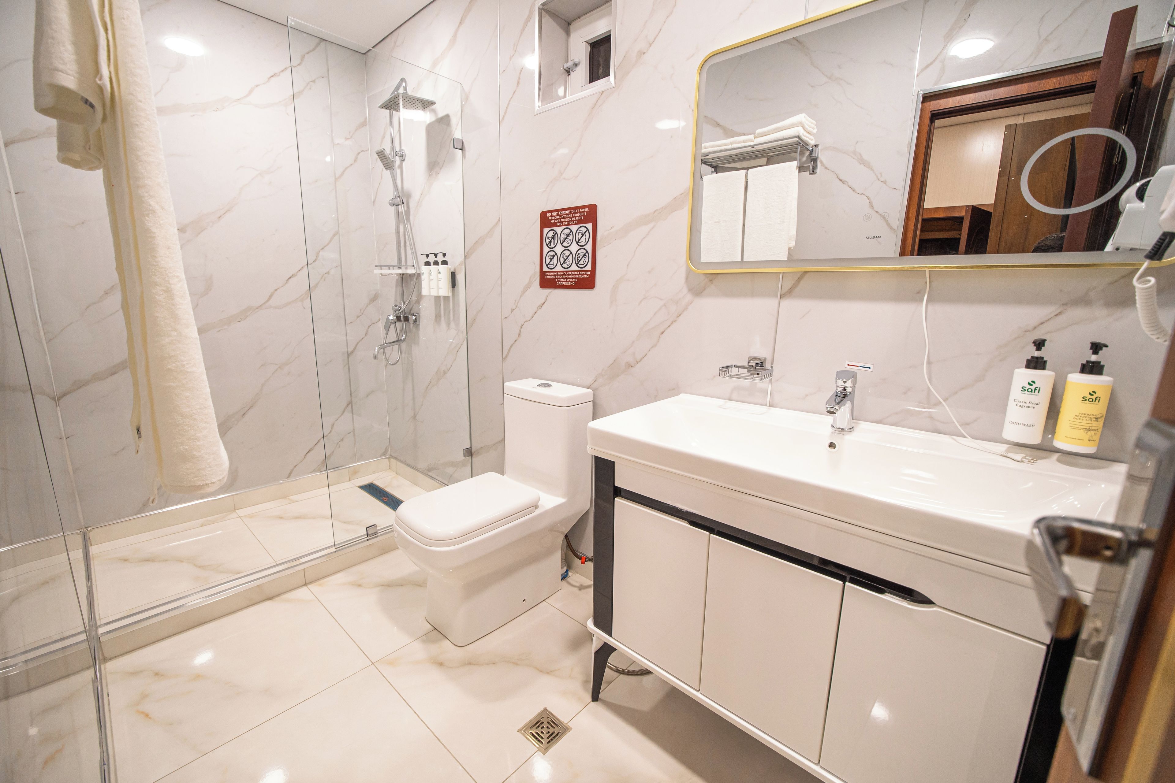 A modern bathroom with a glass-enclosed shower, a toilet, and a vanity with a mirror.