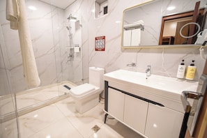A modern bathroom with a glass-enclosed shower, a toilet, and a vanity with a mirror. - Old Bazaar Boutique Hotel (Buxoro)