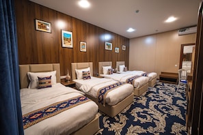 A hotel room with four beds, a large mirror, and a patterned carpet. - Old Bazaar Boutique Hotel (Buxoro)