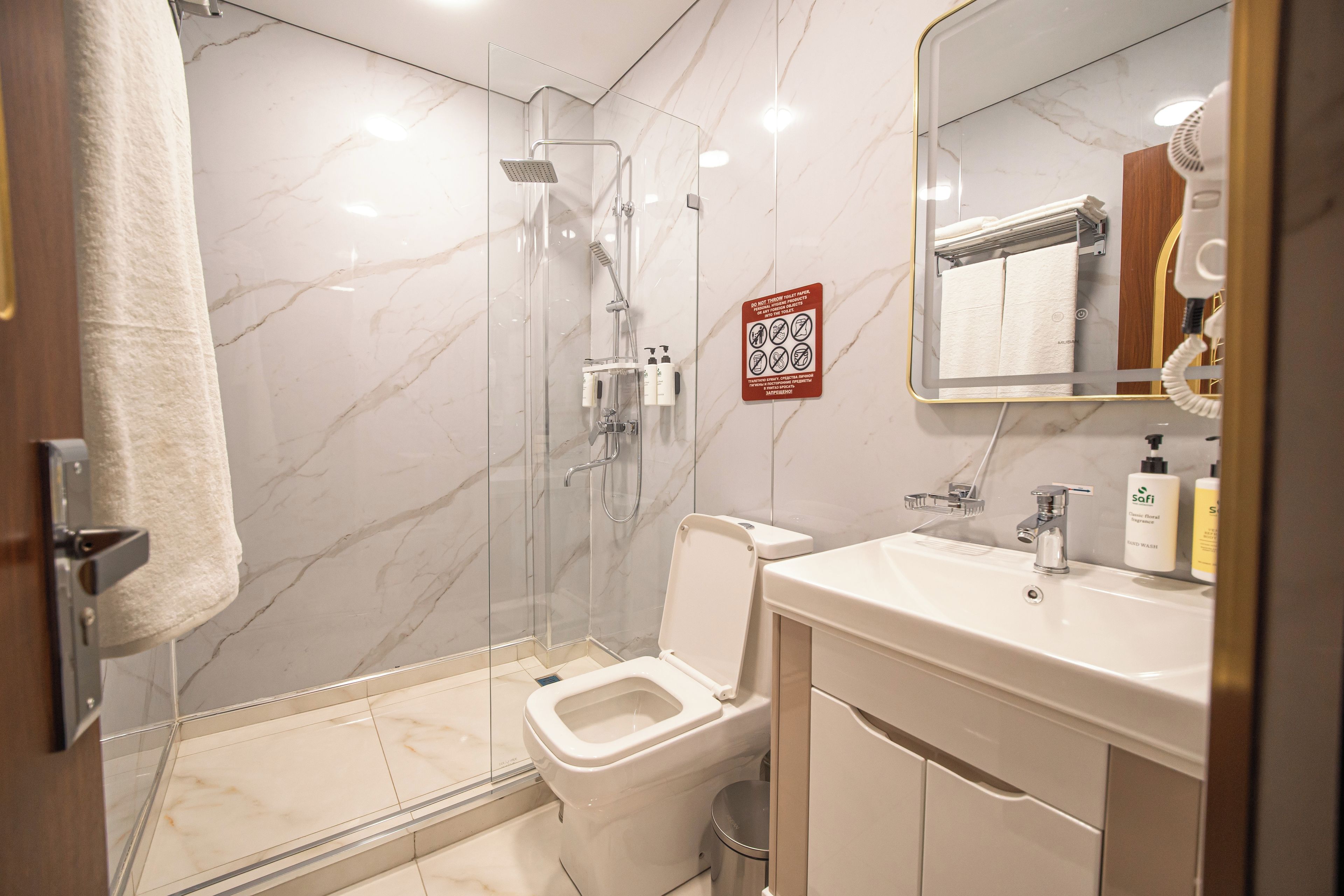 A modern bathroom with a glass-enclosed shower, a toilet, and a sink with a mirror above it.
