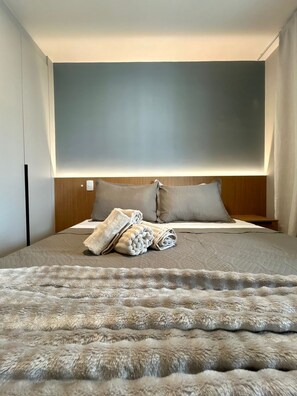 A modern bedroom with a large bed, a headboard, and a fluffy rug. - Level Brooklin 1007 (São Paulo)