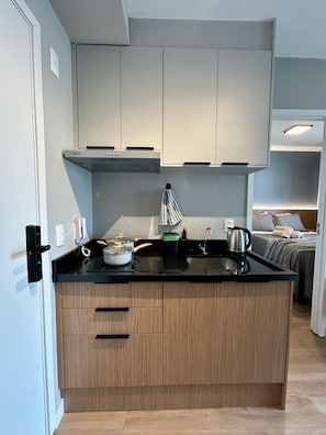 A compact kitchen with a built-in stove, a kettle, and a small sink. - Level Brooklin 1007 (São Paulo)