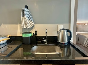A kitchen with a stainless steel sink, a kettle, and a trash bin. - Level Brooklin 1007 (São Paulo)
